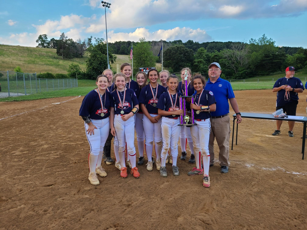 The 2021 Montgomery County 12U Softball All-Stars proudly hold up their district championship trophy.