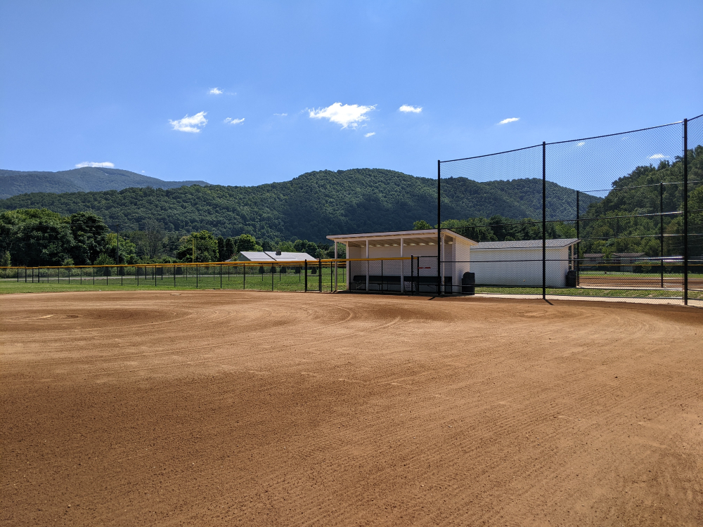 The baseball field at Creed Fields Park is shown on a sunny summer day with a beautiful mountain backdrop.