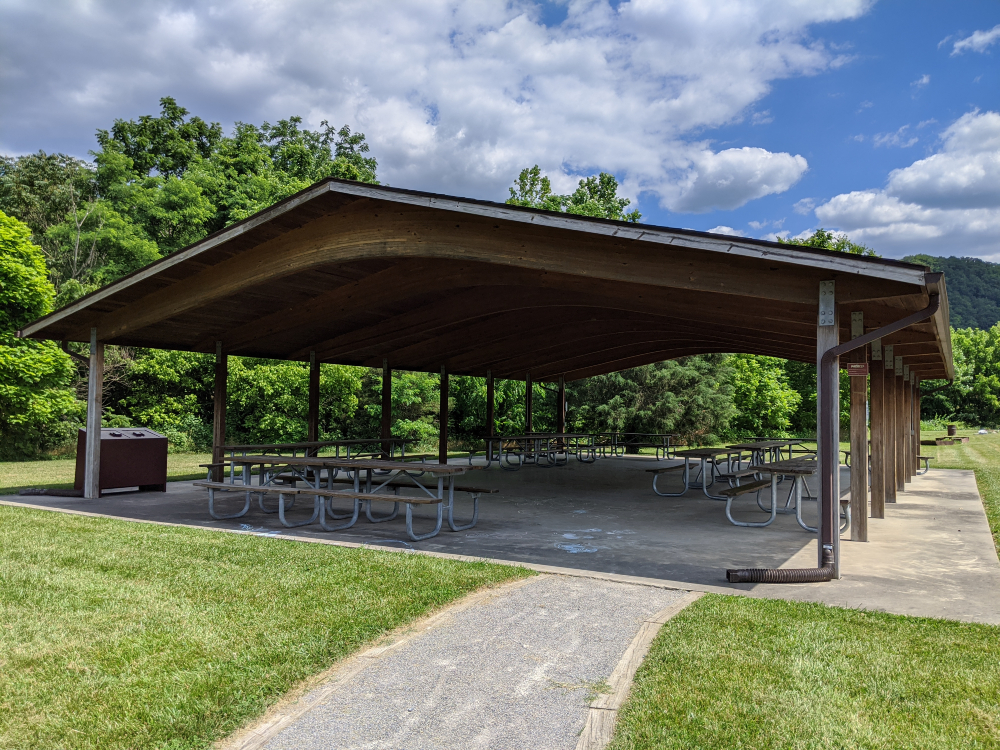 The picnic shelter at Eastern Montgomery Park is bordered by trees and green space on a sunny summer day.