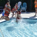 Children wearing life vests jump into the Frog Pond Pool.
