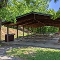 The picnic shelter at Mid County Park is located under shade trees next to the restroom.