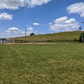 The baseball field at Motor Mile Park is situated under a large grassy hill.