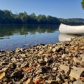 A canoe rests along the New River shoreline at the Whitethorne Boat Launch on a summer day.